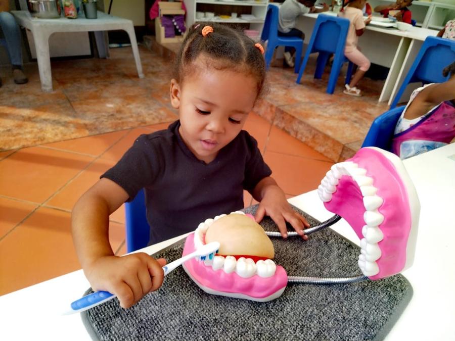 Girl brushing a giant model of teeth
